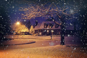 Snowy street scene at night with an attractive house lit up in the snow