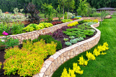 Three layers of terraced garden beds filled with shrubs and supported by decorative concrete walls